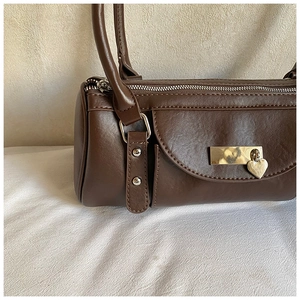 Détail du sac bowling en cuir marron foncé montrant le pendentif cœur et la poche