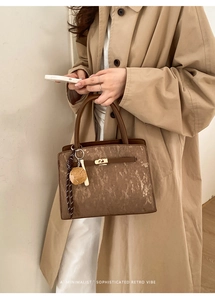 Détail d'un sac bandoulière marron texturé avec fermoir doré et perles décoratives