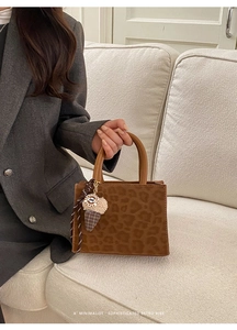 Detail of leopard print baguette bag featuring suede texture and decorative charms