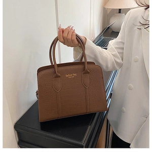 Dettaglio borsa marrone con trama a coccodrillo e scritta NEW YORK dorata in ufficio casa