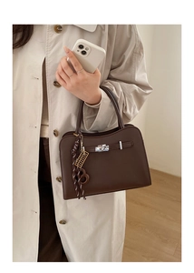 Detail of dark brown leather handbag with silver twist lock and decorative charms