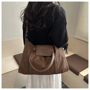 Brown textured large travel bag shown on a model for scale and shoulder carry style
