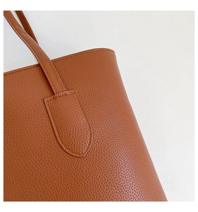 Close-up of caramel pebble grain leather tote bag with reinforced stitching and handle detail