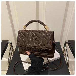 Detail of dark brown patent leather shoulder bag featuring embossed FASHION lettering