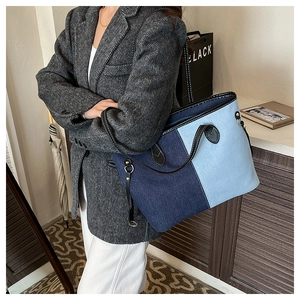 Detail of color-block patchwork tote bag with denim texture and leather straps on model