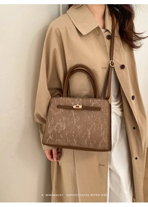 Gros plan d'un sac à main rétro marron grainé porté avec un trench classique