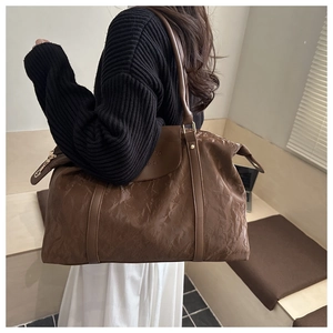 Detailed side view of large brown crinkled tote bag showing texture and slim shoulder straps