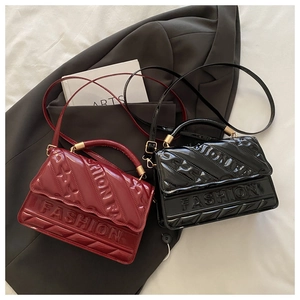 Detail of burgundy and black patent leather crossbody bags with embossed fashion letters
