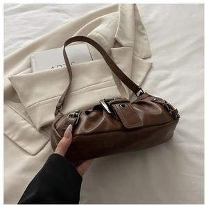 Close-up of vintage brown PU leather shoulder bag with metallic buckle and retro texture