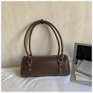 Detail of dark brown bowling bag with silver studs and long thin shoulder straps