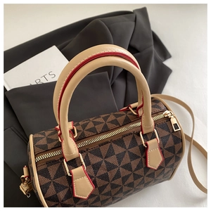 Detail of geometric pattern boston bag with beige handles and gold hardware