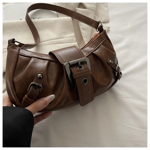 Macro detail of brown retro hobo bag featuring vintage metal buckle and pleated PU leather