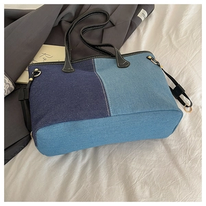 Detail of large denim patchwork tote bag with black leather handles and gold hardware