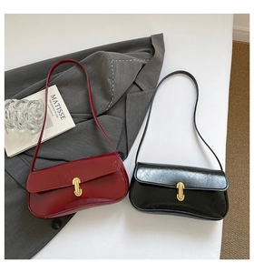 Detail of red and black leather underarm bags with gold metal clasps and glossy texture