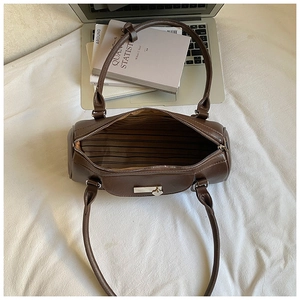 Top view of brown cylinder bag showing striped lining and heart charm detail