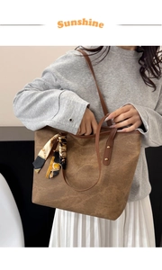 Detail of canvas tote bag with leather trim, rivets, and decorative vintage print scarf