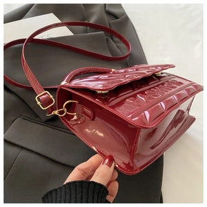 Detail of red patent leather shoulder bag with embossed FASHION text and gold hardware