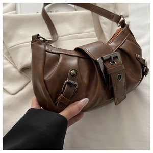 Close-up of vintage dark brown faux leather bag with aged metal buckles and rivets