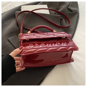 Detail of burgundy patent leather bag with quilted diamond pattern and FASHION logo