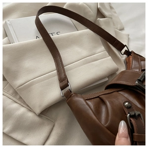 Detail of vintage brown leather shoulder bag featuring pleated texture and metal buckle