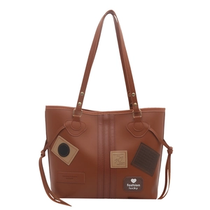 Brown large capacity tote bag with decorative patches and metal rivets on shoulder straps