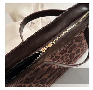 Detail view of smooth golden metal zipper and leopard print texture on tote bag