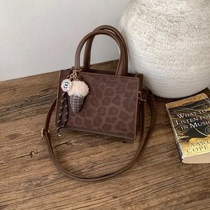 Stylish leopard print tote bag with adjustable strap and ice cream charm on a desk