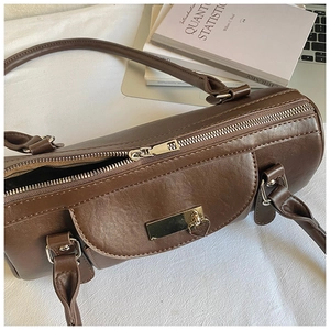 Detail of dark brown bowling handbag with gold heart pendant and metal zipper closure