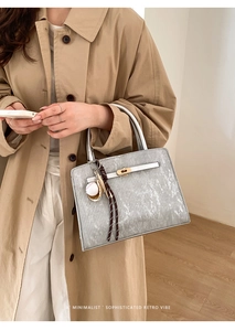 Détail du sac seau gris argenté avec texture brossée et fermoir pivotant en métal doré