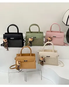 Detail view of woven leather Kelly bags in various colors with cat charms and metal locks
