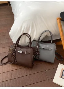 Detail view of lychee pattern leather handbag with metal buckle and decorative pendant