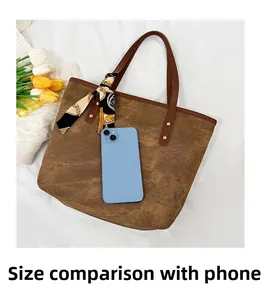 Brown canvas tote bag with silk scarf detail next to a smartphone for size comparison