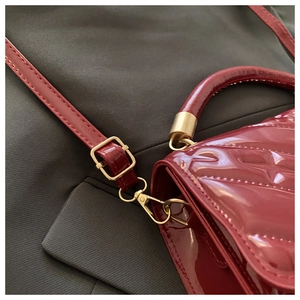 Detail of burgundy patent leather embossed texture and luxury golden hardware