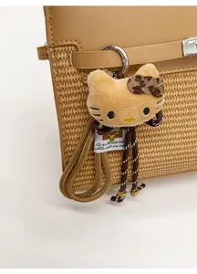 Close-up of plush cat charm with leopard print bow on a straw handbag detail