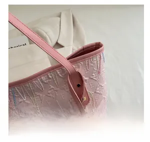 Detailed view of pink tote bag with embossed letter patterns and colorful embroidery fringe