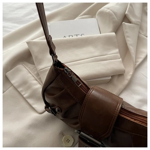 Detailed view of dark brown vintage leather shoulder bag on a stylish suit background