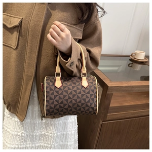 Detail of Boston handbag featuring geometric patterns, red edge paint and gold buckles