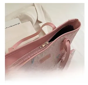 Detail view of pink embroidered tote bag with premium golden zipper and smooth metal plaque