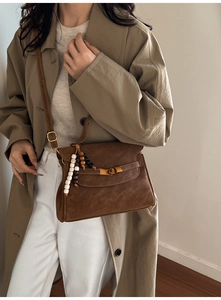 Detail of vintage dark brown crossbody bag with gold twist lock and bead charm decor