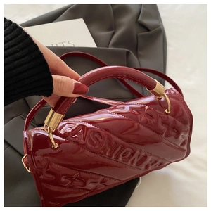 Close-up of wine red patent leather handbag with quilted texture and gold hardware