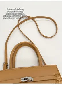 Detail of caramel leather and straw handbag featuring a silver twist lock and strap