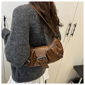 Close-up of vintage brown shoulder bag featuring textured faux leather and metal buckle