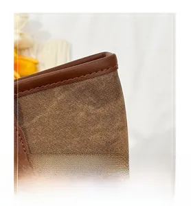 Close-up of canvas tote bag with brown leather trim and golden metal rivet details