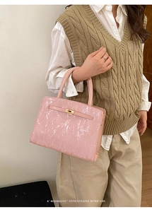 Détail du sac carré vintage rose avec fermoir doré porté par un mannequin en tenue chic