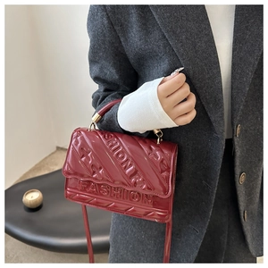 Close-up of wine red patent leather shoulder bag with embossed FASHION lettering