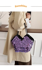 Macro shot of large purple sequined tote bag with black straps worn by a model