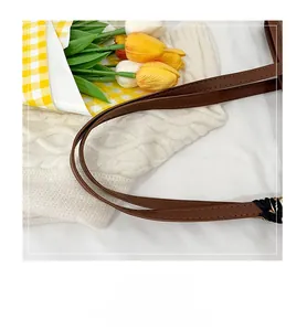 Detailed view of premium brown leather handles with precise stitching on a tote bag