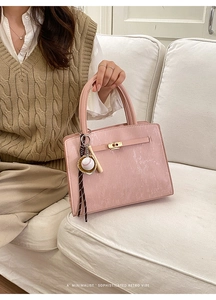 Détail du sac à main rose texturé avec fermoir doré et breloque baseball de luxe