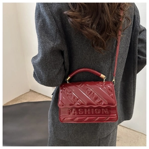 Detail of red patent leather handbag featuring embossed Fashion logo and stars