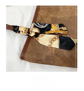 Detail of coffee brown tote bag handle with elegant printed silk scarf accessory